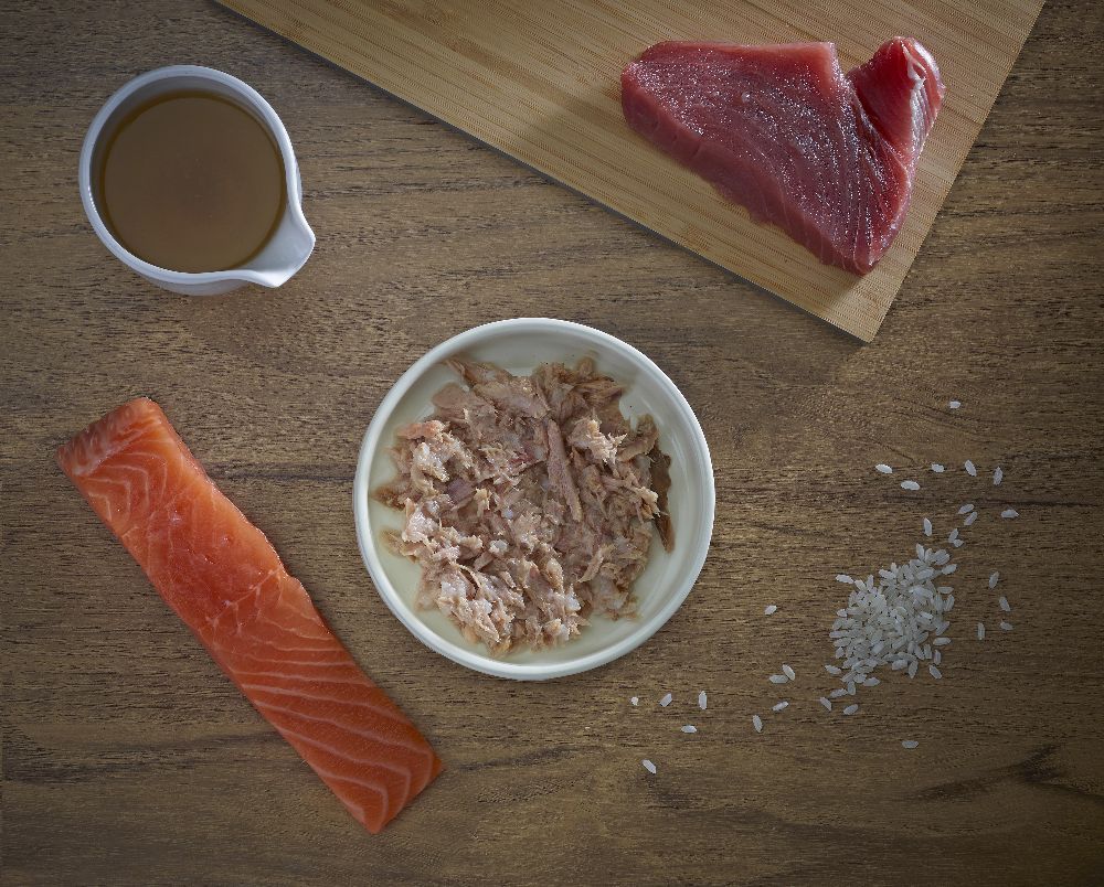 Zusammensetzung aus Thunfisch, Lachs, Soße und Reis auf Holzbrett. Zutaten für Katzenfutter.