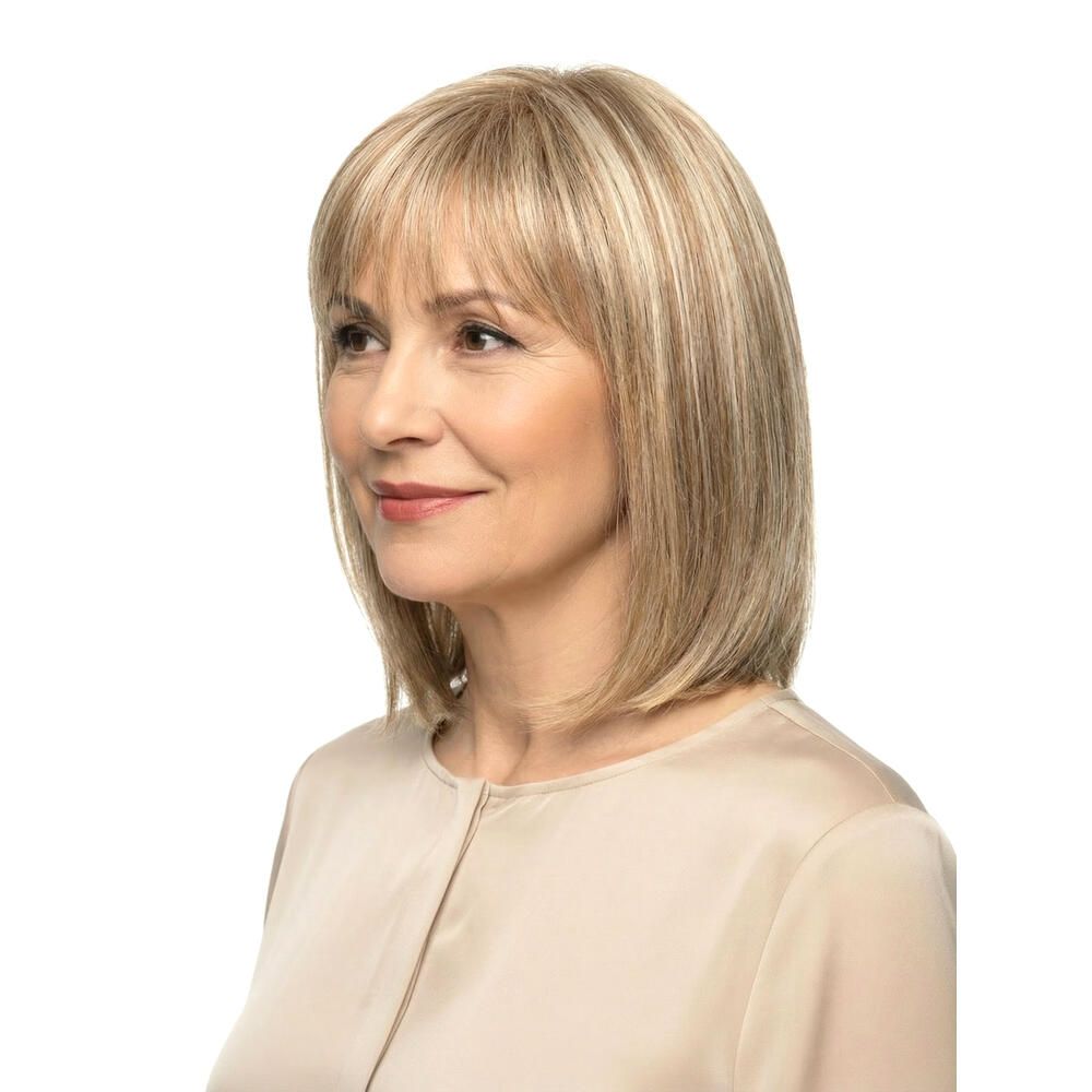 Blond gefärbte Perücke mit Pony. Mittellange, gestufte Haare. Frau mit hellem Oberteil. Seitenansicht.