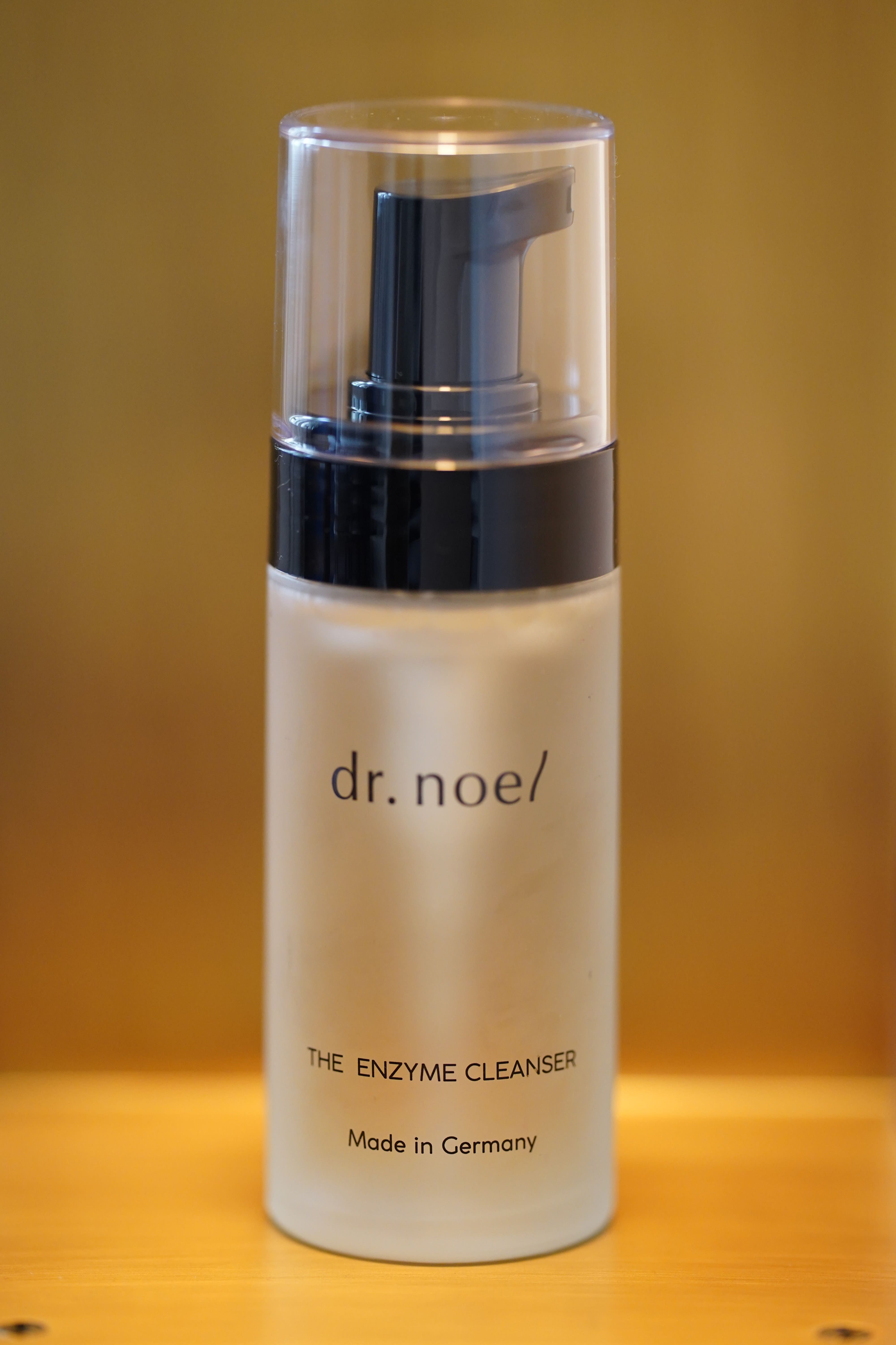 Flasche mit Sprühkopf. Aufschrift: dr. noel/ THE ENZYME CLEANSER. Hergestellt in Deutschland. Steht auf einem Regal.