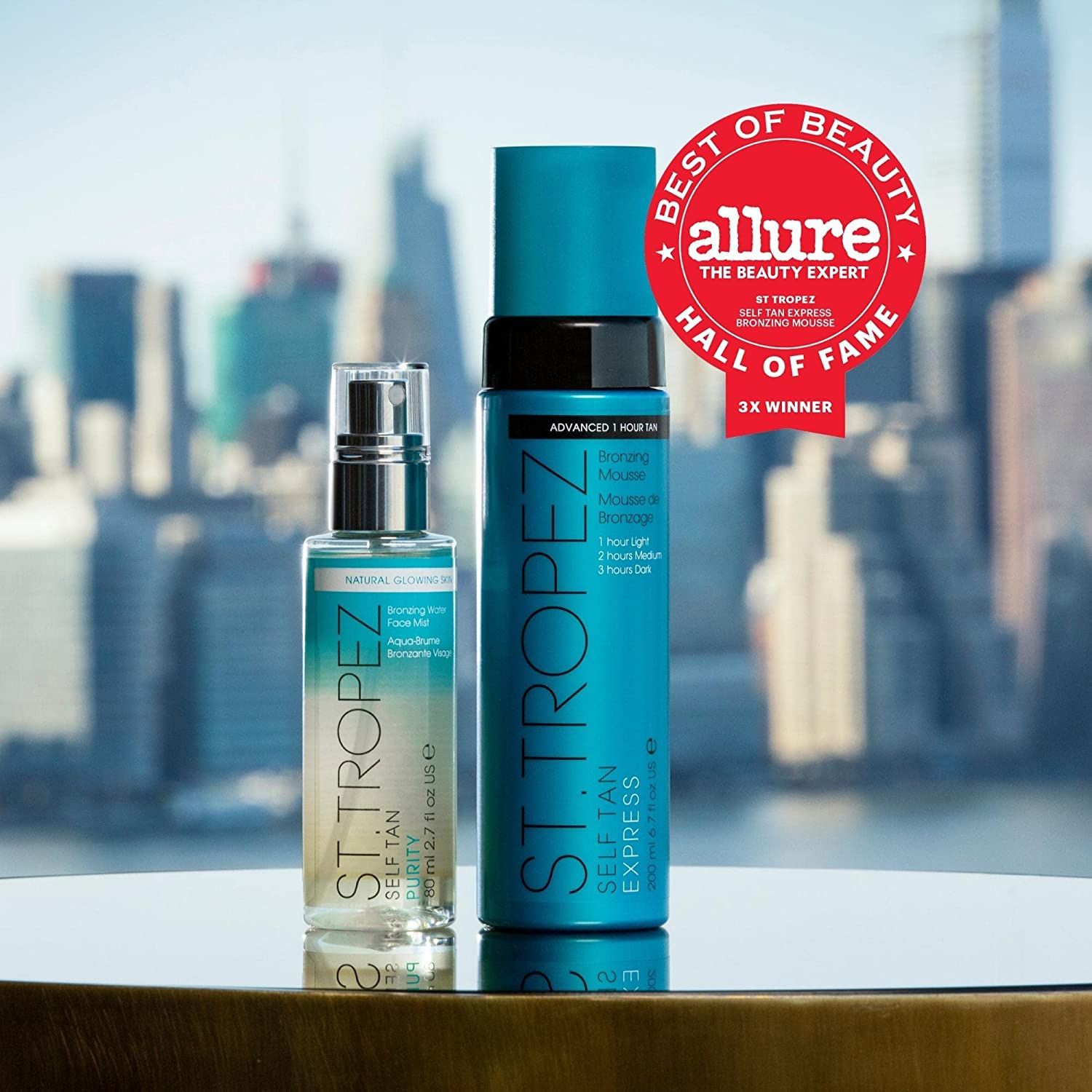 Zwei Flaschen vor einem verschwommenen Stadtbild. Eine Flasche St.Tropez Self Tan Express, die andere mit der Aufschrift Natural Bronzing.