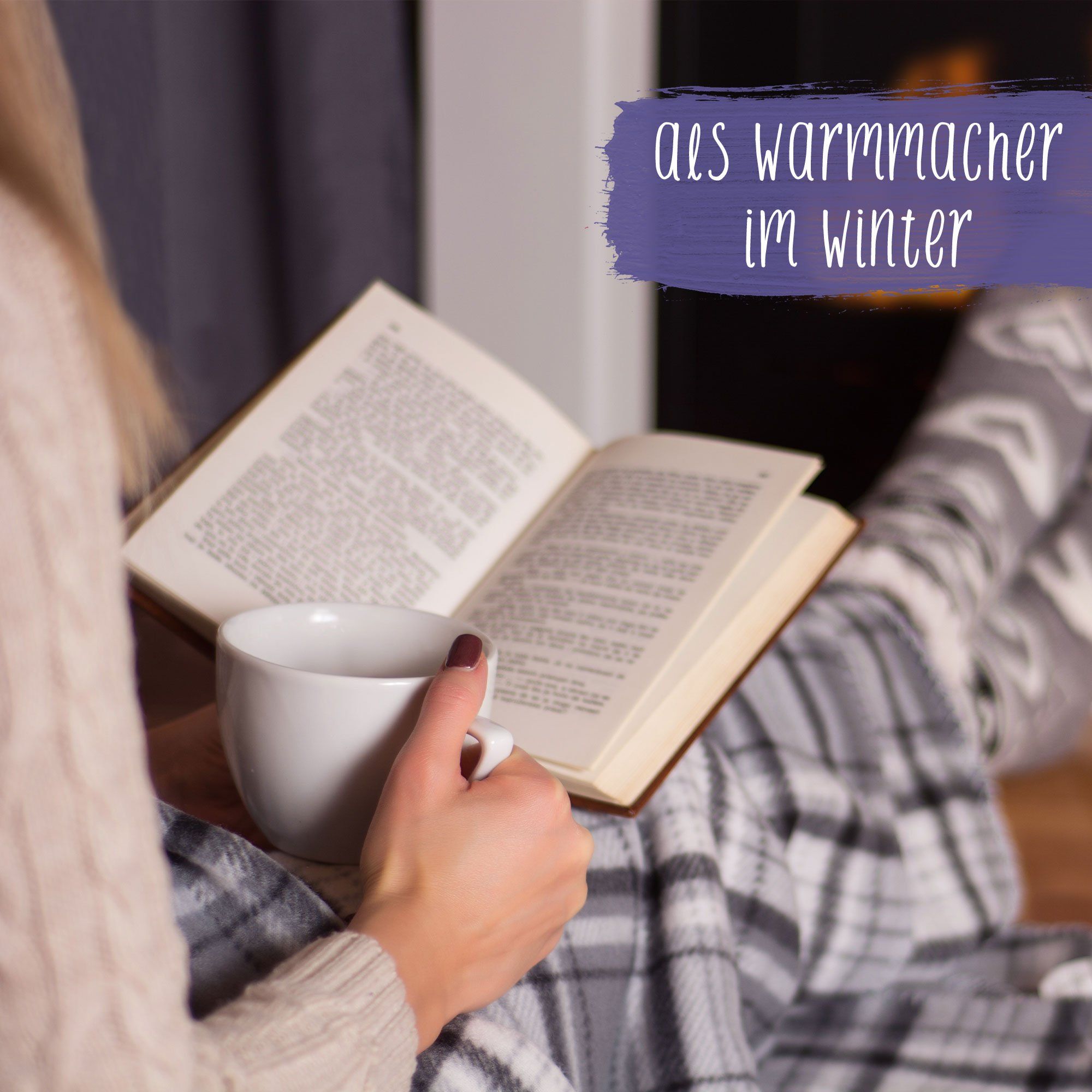 Person sitzt mit Buch und Tasse vor Kamin. Person trägt karierte Hose und Socken.