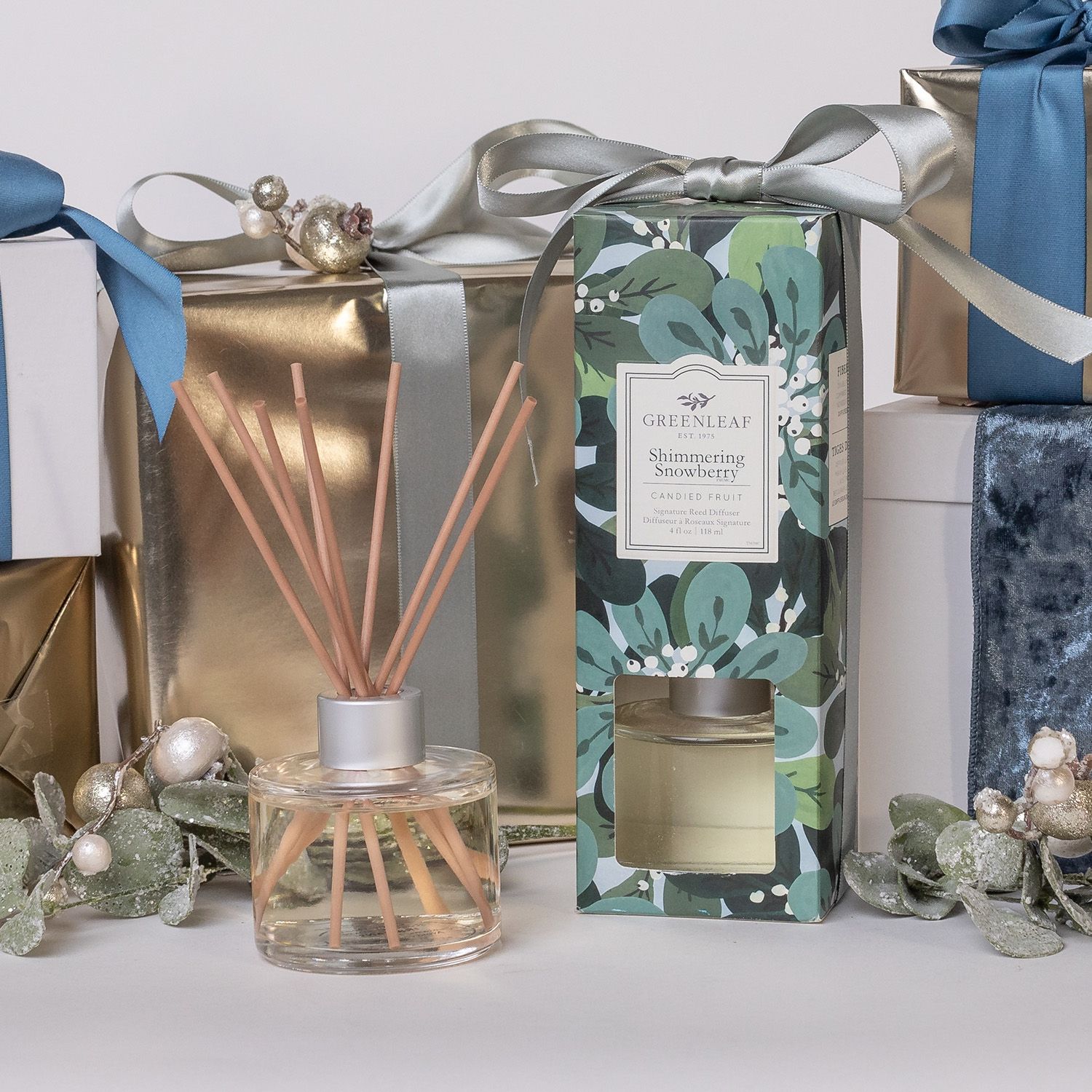 Glasflakon mit Duftstäbchen und Verpackung, umgeben von Geschenkboxen.