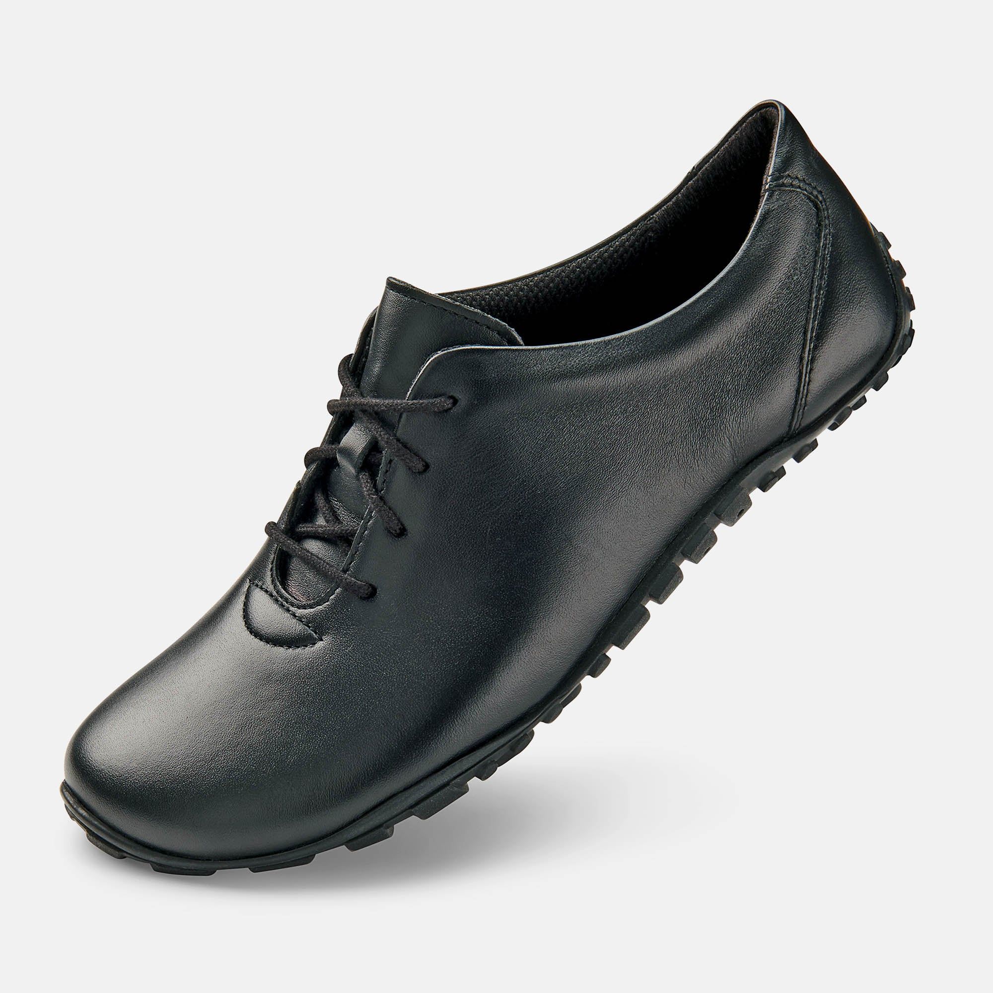 Schwarzer Herren-Schnürschuh. Lederoptik, breite Passform. Schnürung, flache Sohle. Schuh leicht schräg gestellt, von der Seite.