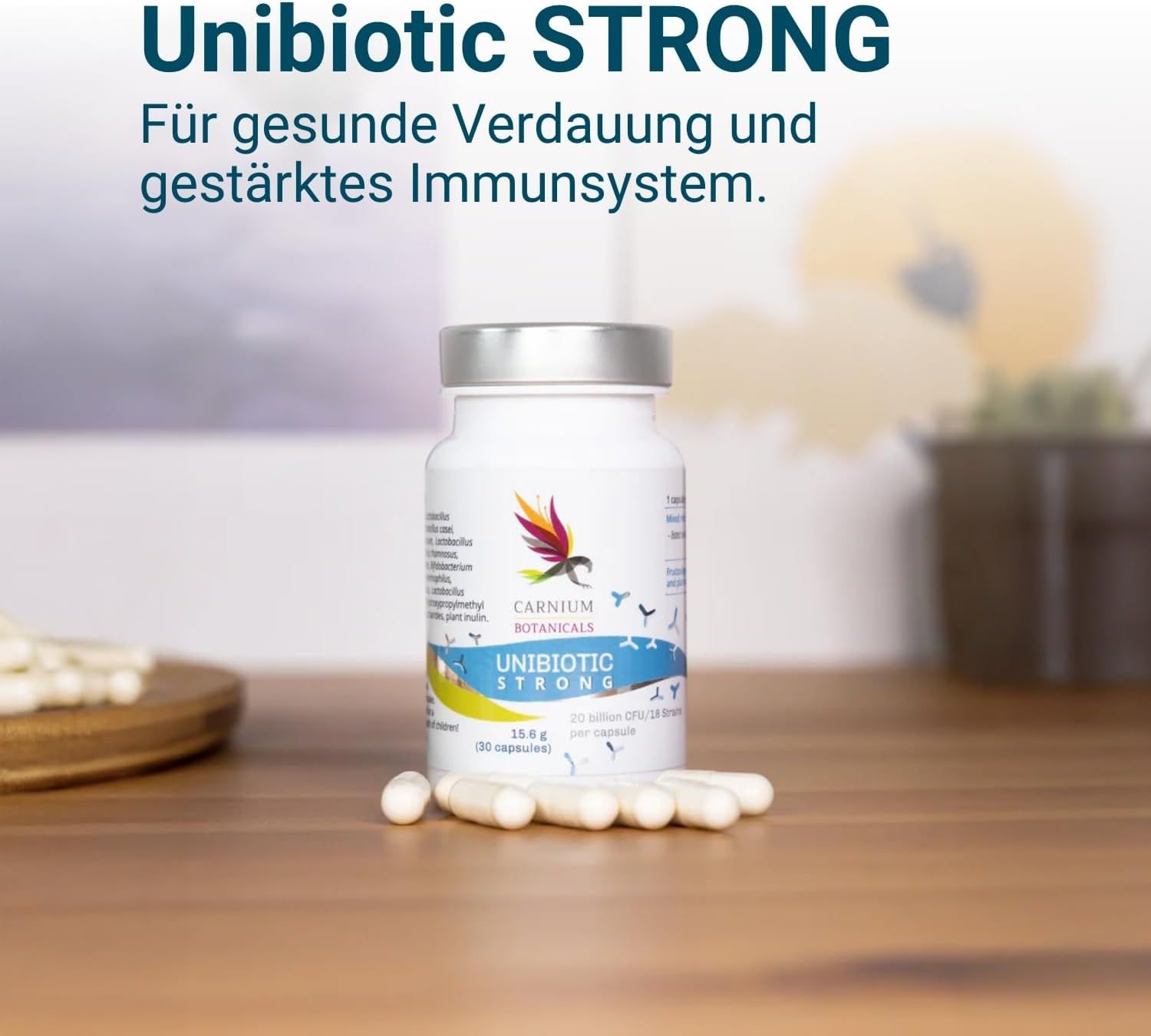Flasche mit Kapseln auf Holzoberfläche. Aufschrift: Unibiotic STRONG, 20 Milliarden CFU/15 Stämme. Marke: CARNIUM BOTANICALS. Kapseln daneben.