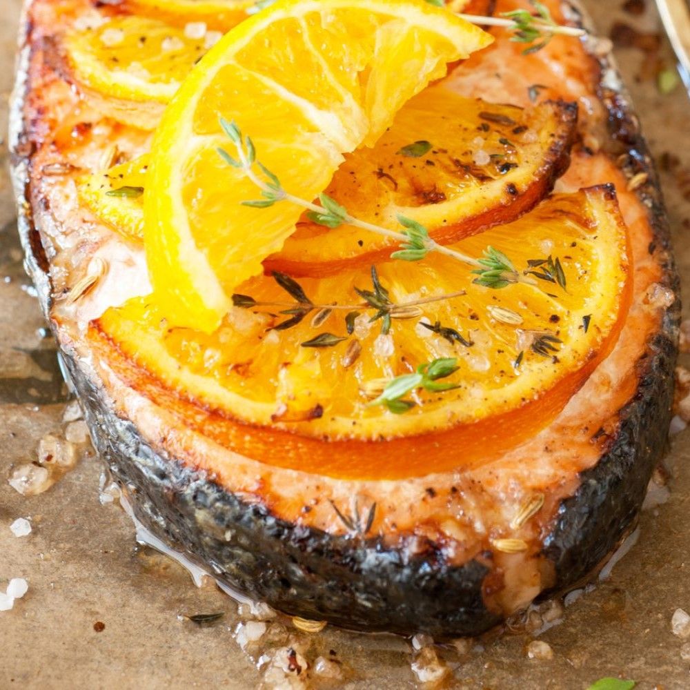 Gegrillter Lachs mit Orangenscheiben. Thymianzweige. Auf Backpapier. Nahaufnahme.