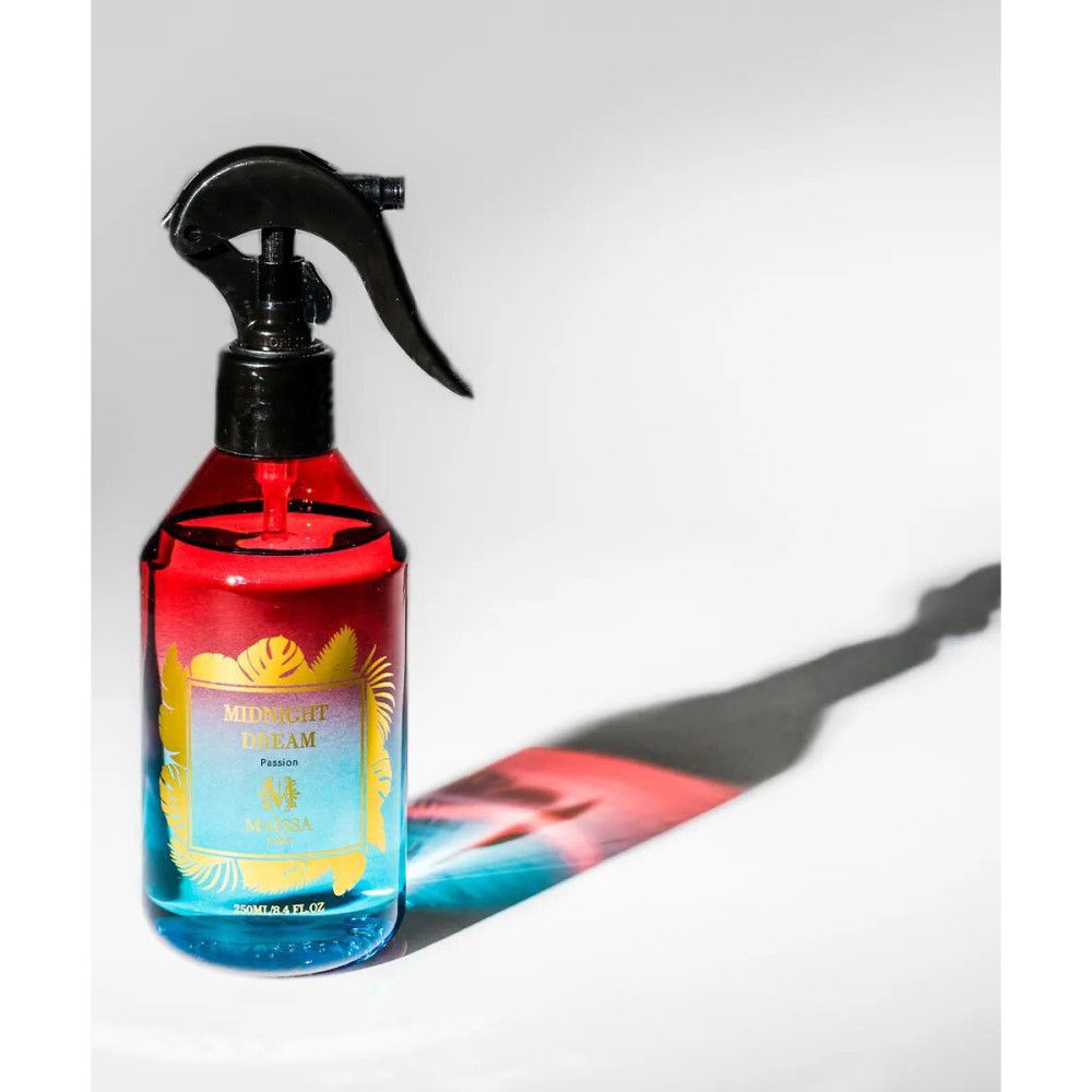 Blau-rote Sprühflasche mit schwarzem Sprühkopf. Aufschrift: Midnight Dream, Maïssa. Schatten auf weißem Hintergrund.