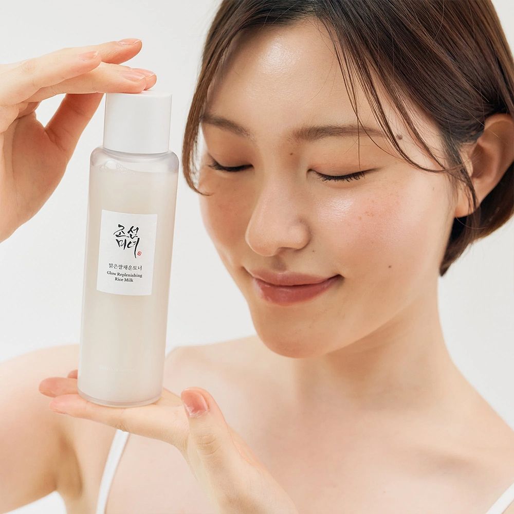 Frau hält eine Flasche BEAUTY OF JOSEON Glow Replenishing Rice Milk.