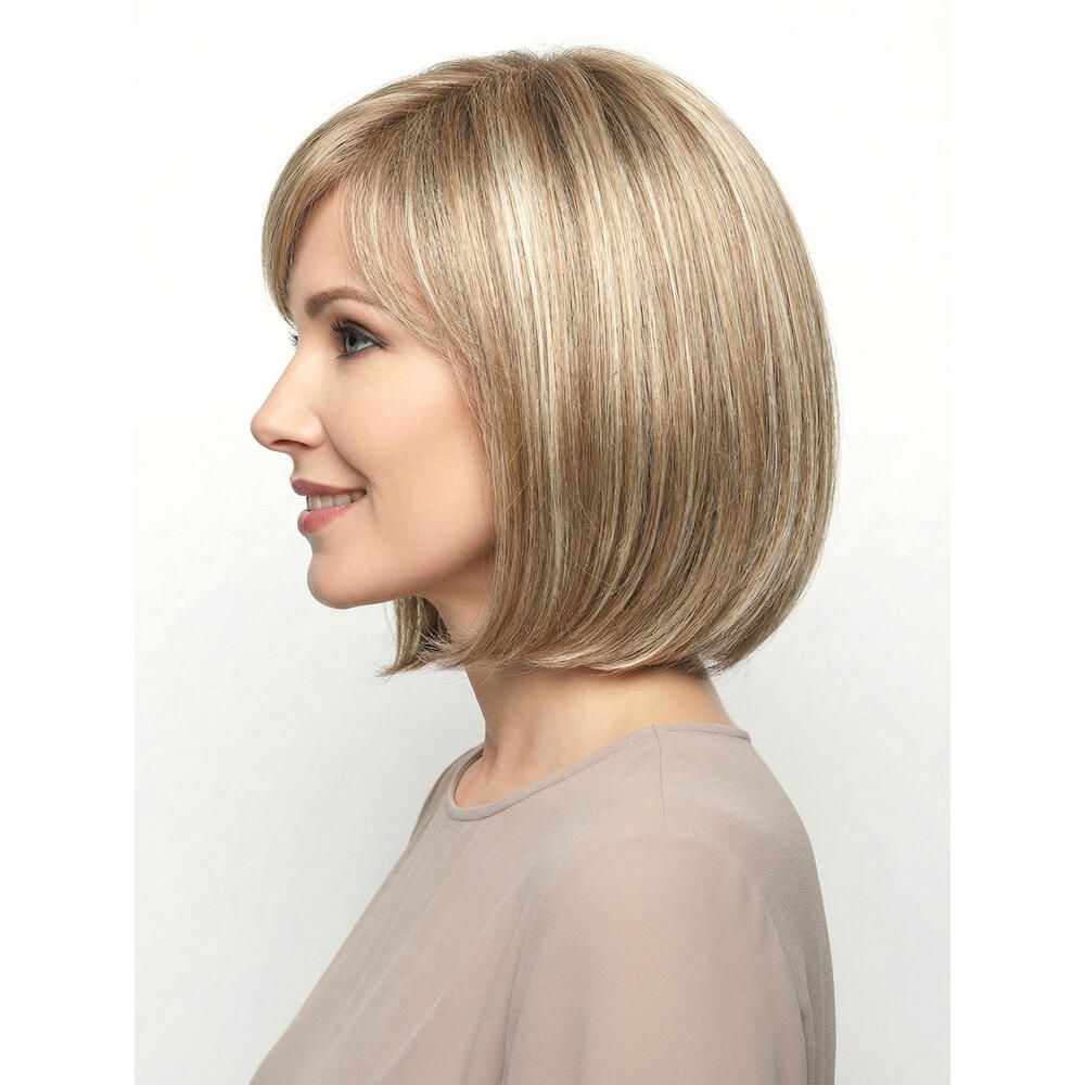 Perücke mit kurzem, blondem Haar und Pony. Die Frau trägt ein beiges Oberteil. Seitenansicht.