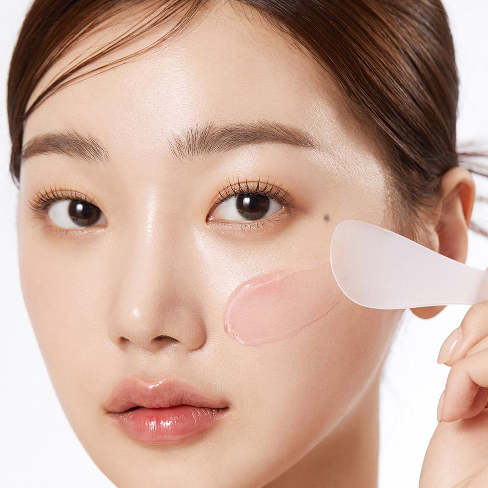 Frau mit Hautpflege. Spatel mit rosa Creme. Text: Collagen Jelly Cream.