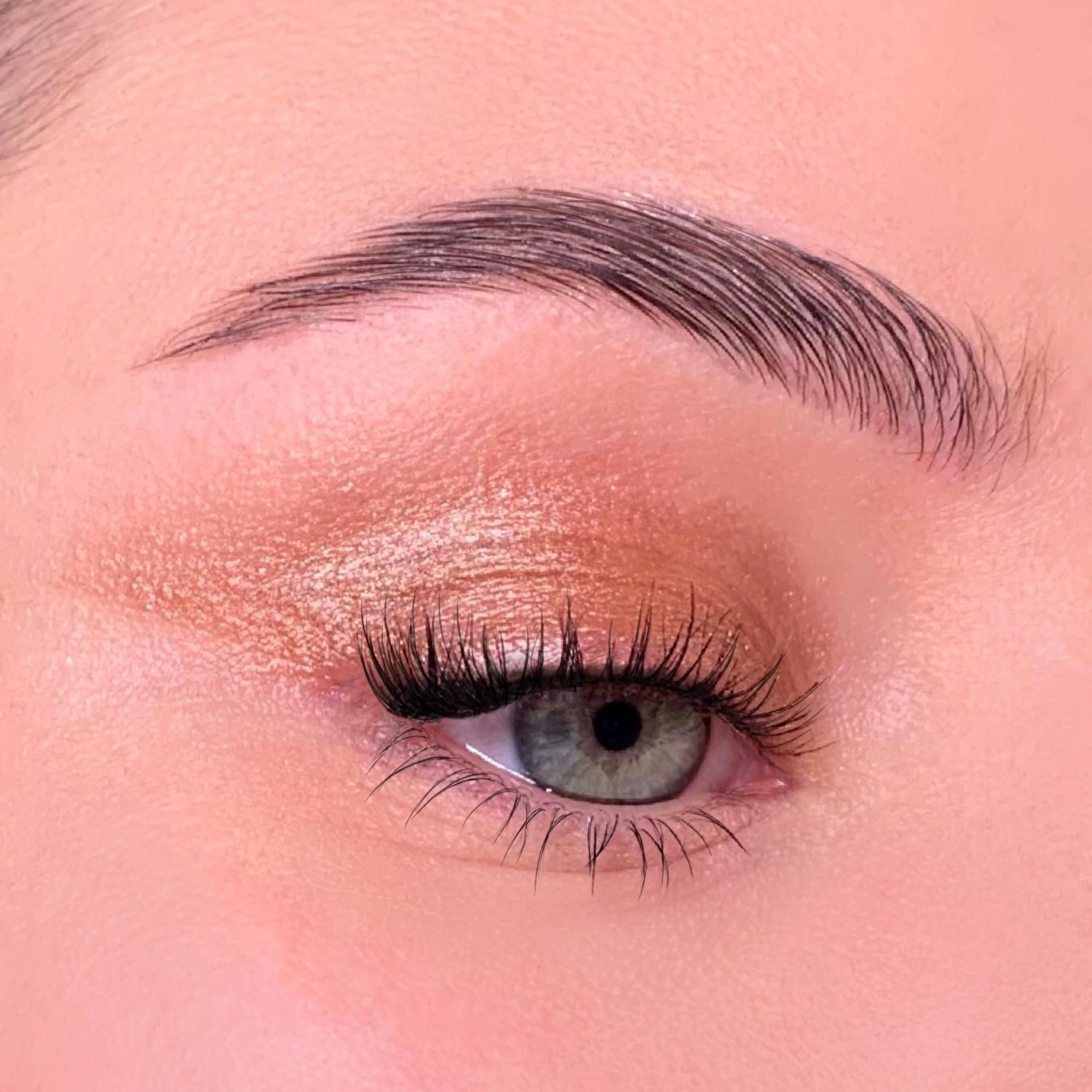 Nahaufnahme eines geschminkten Auges. Lidschatten in Goldtönen. Braue und Wimpern.