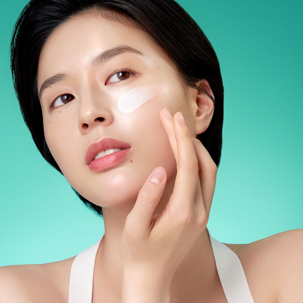 Frau trägt Purito Mighty Bamboo Panthenol Cream auf ihre Wange auf.