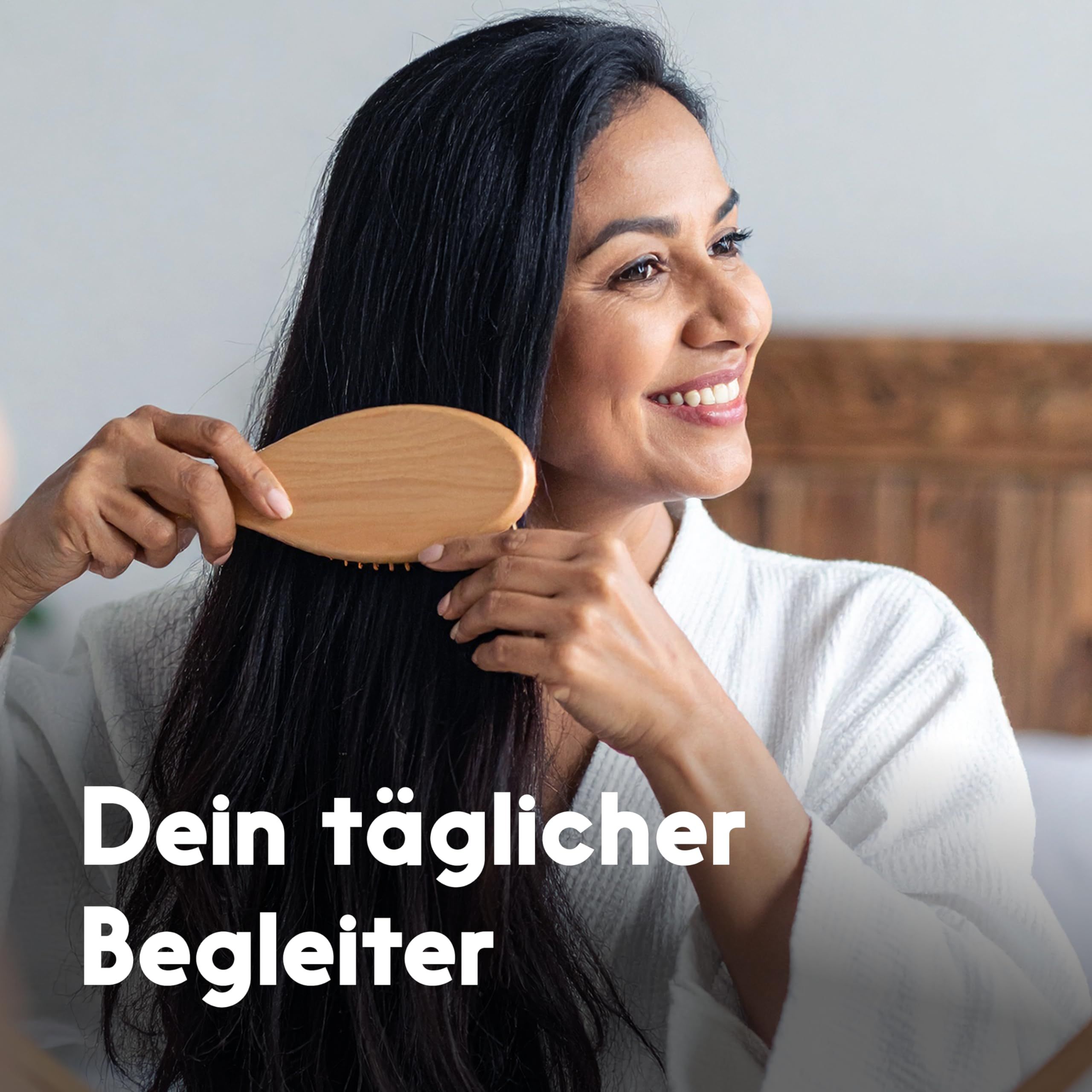 Frau bürstet ihr langes, schwarzes Haar mit einer Holzhaarbürste. Text: Dein täglicher Begleiter.