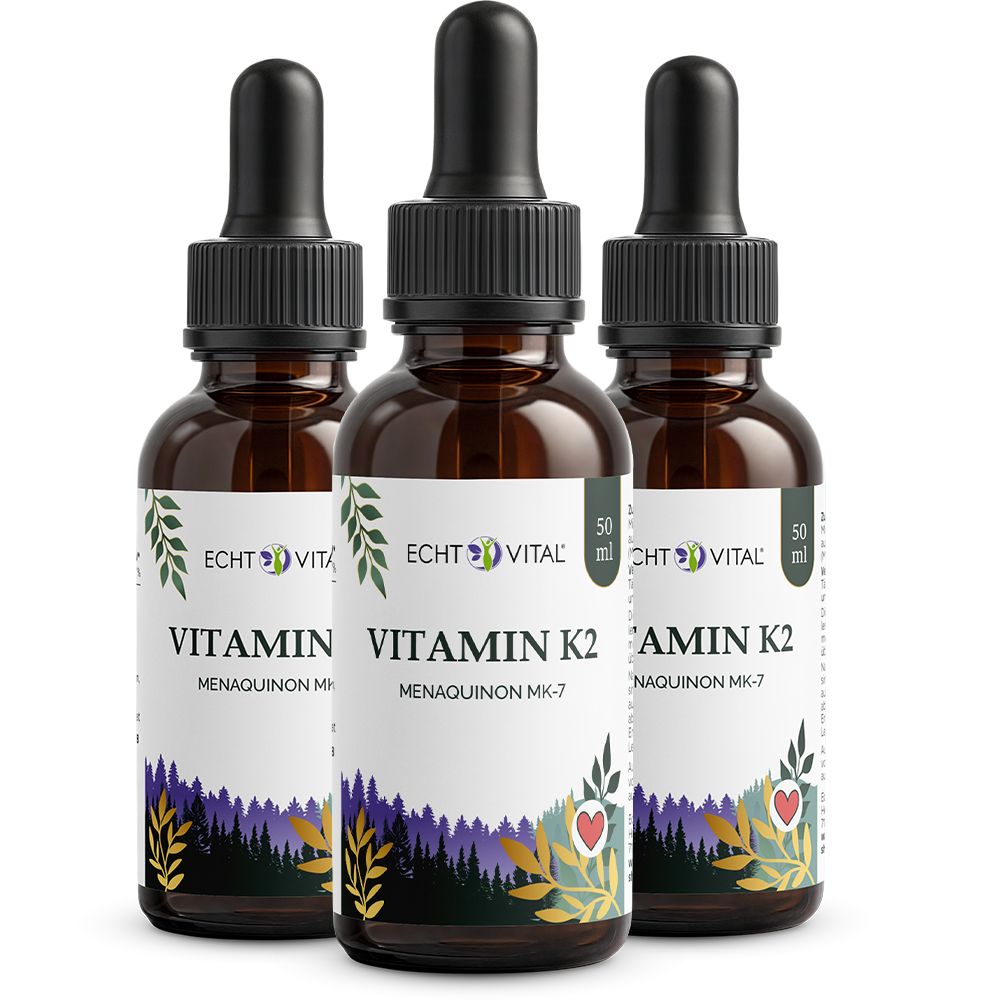 Drei Flaschen Echt Vital Vitamin K2 Tropfen mit Pipettenverschluss. Braune Glasflaschen mit Etiketten, die einen Wald und ein Herz zeigen.