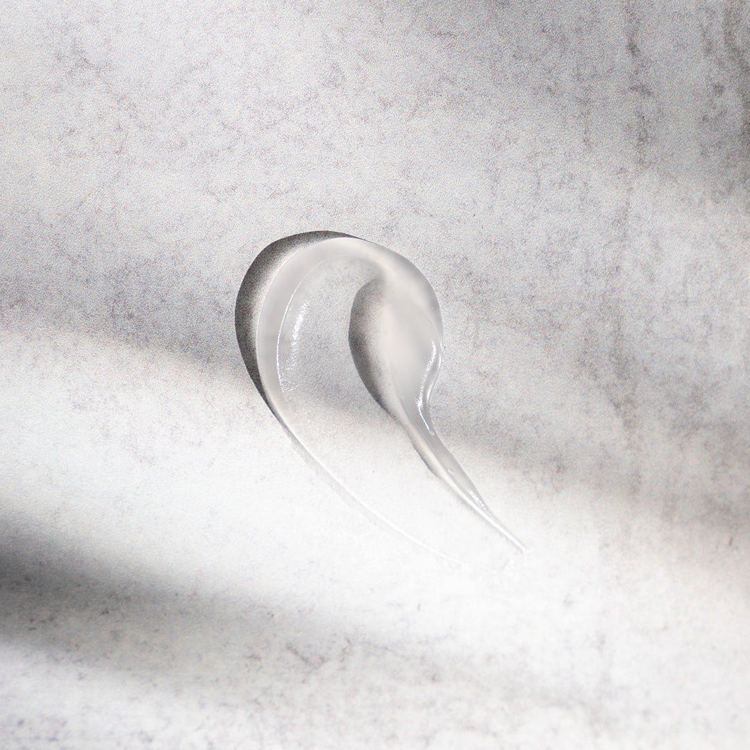 Klare, gelartige Substanz, wellenförmig auf hellem Untergrund. Konsistenz sichtbar.