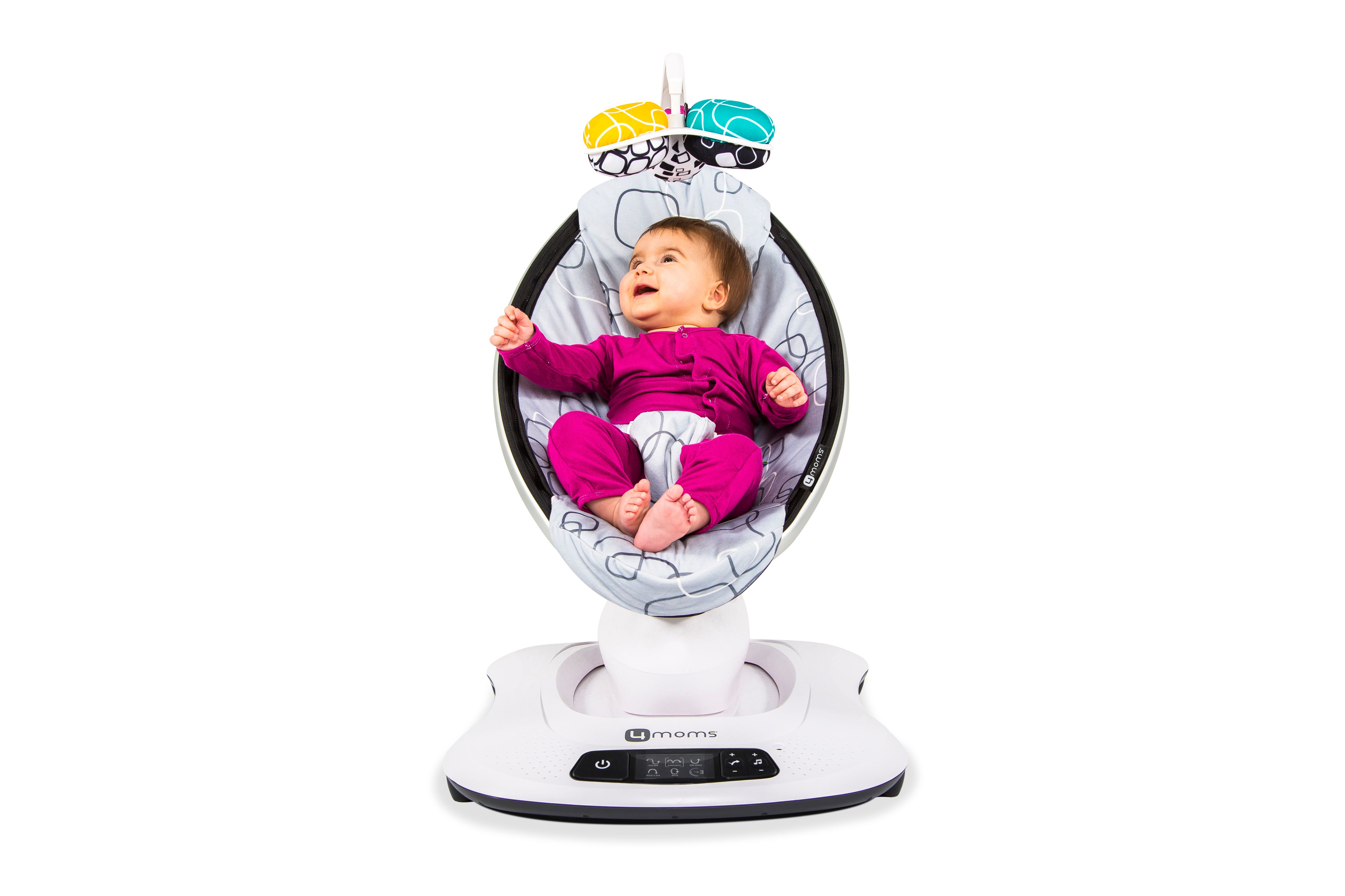 Baby in Babywippe. Grauer Sitz mit Muster, Spielzeug. Kind trägt rosa Kleidung. Frontansicht.