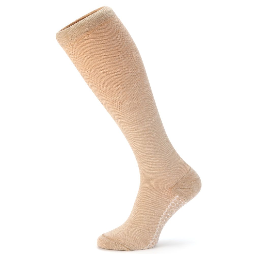 Beige Kniestrümpfe. Feines Material, leicht schräg gestellt. Weiße, strukturierte Sohle. Auf weißem Hintergrund.