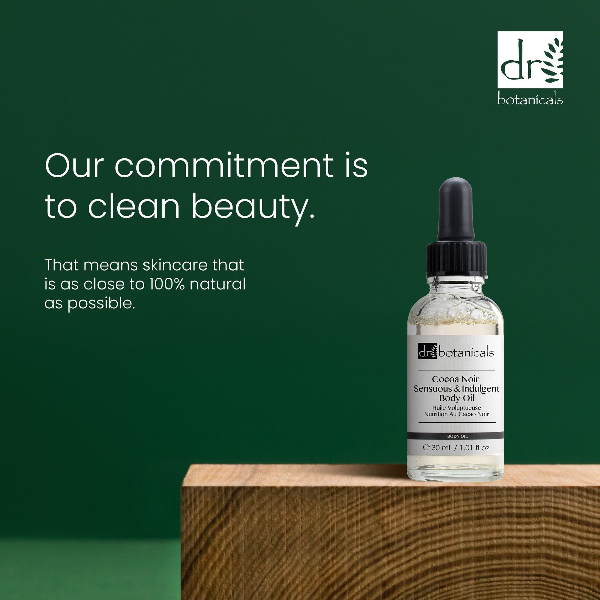 Produktflasche auf Holzblock. Text: 'Our commitment is to clean beauty'. Marke und Produktname auf Etikett.