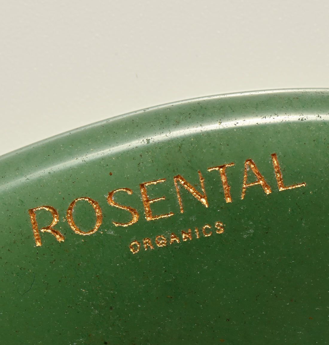 Nahaufnahme des grünen Gua Sha. Rosental Organics-Logo in Gold eingraviert.