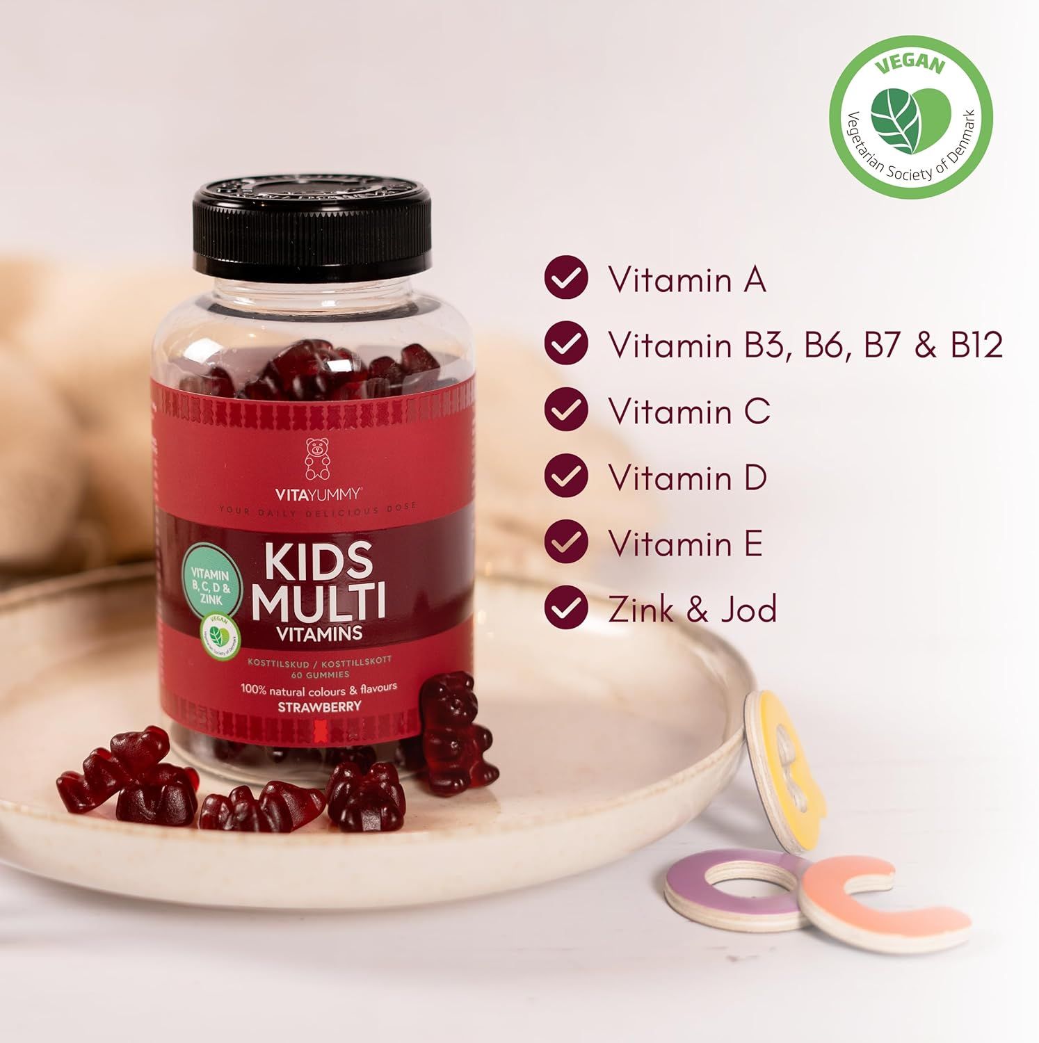 Glasflasche mit roten Gummibärchen. Aufschrift: KIDS MULTI VITAMINS. Enthält Vitamin A, B3, B6, B7, B12, C, D, E, Zink & Jod. Vegan-Siegel.