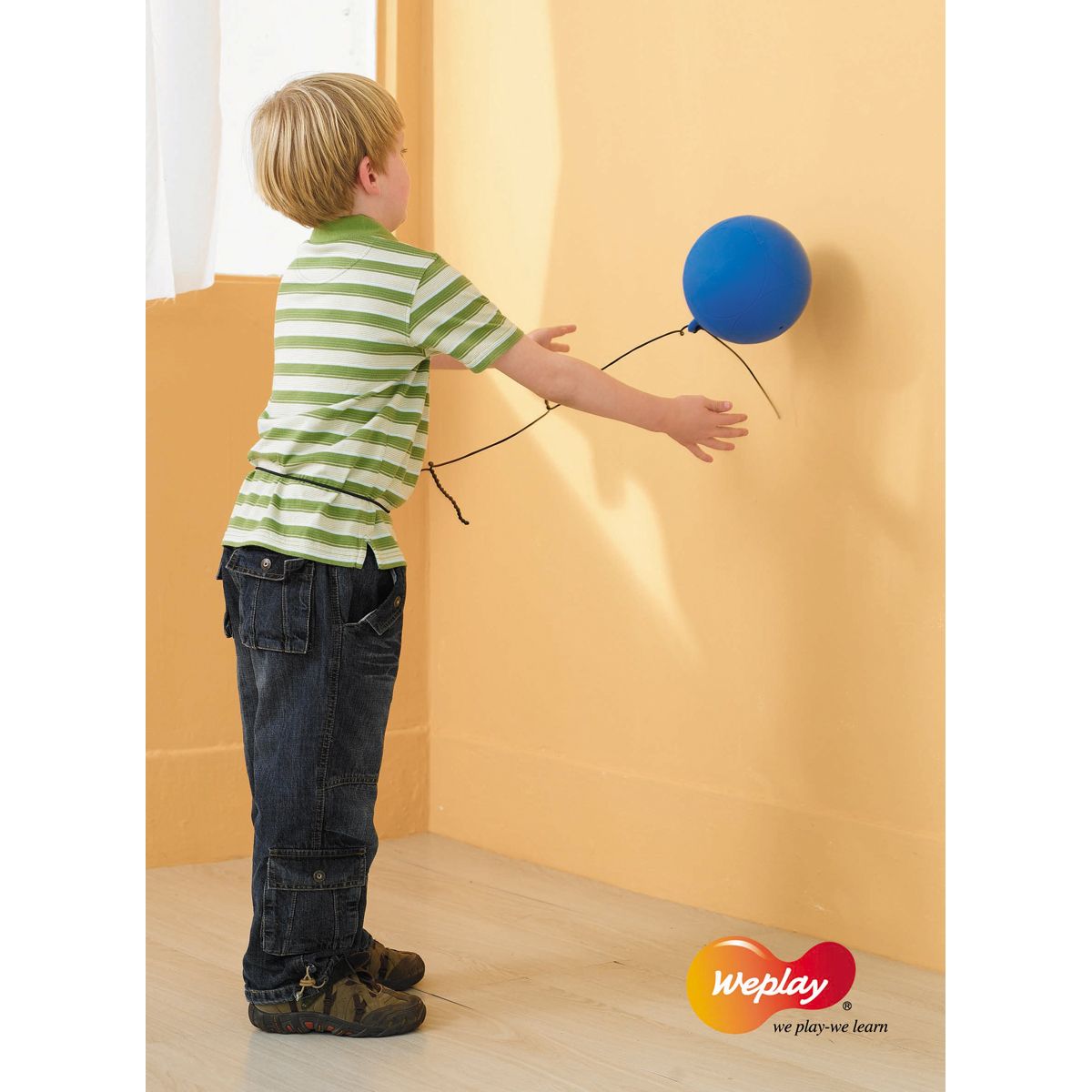 Kind berührt blauen Ball an Wand. Ball an Schnur. Logo 'weplay'.
