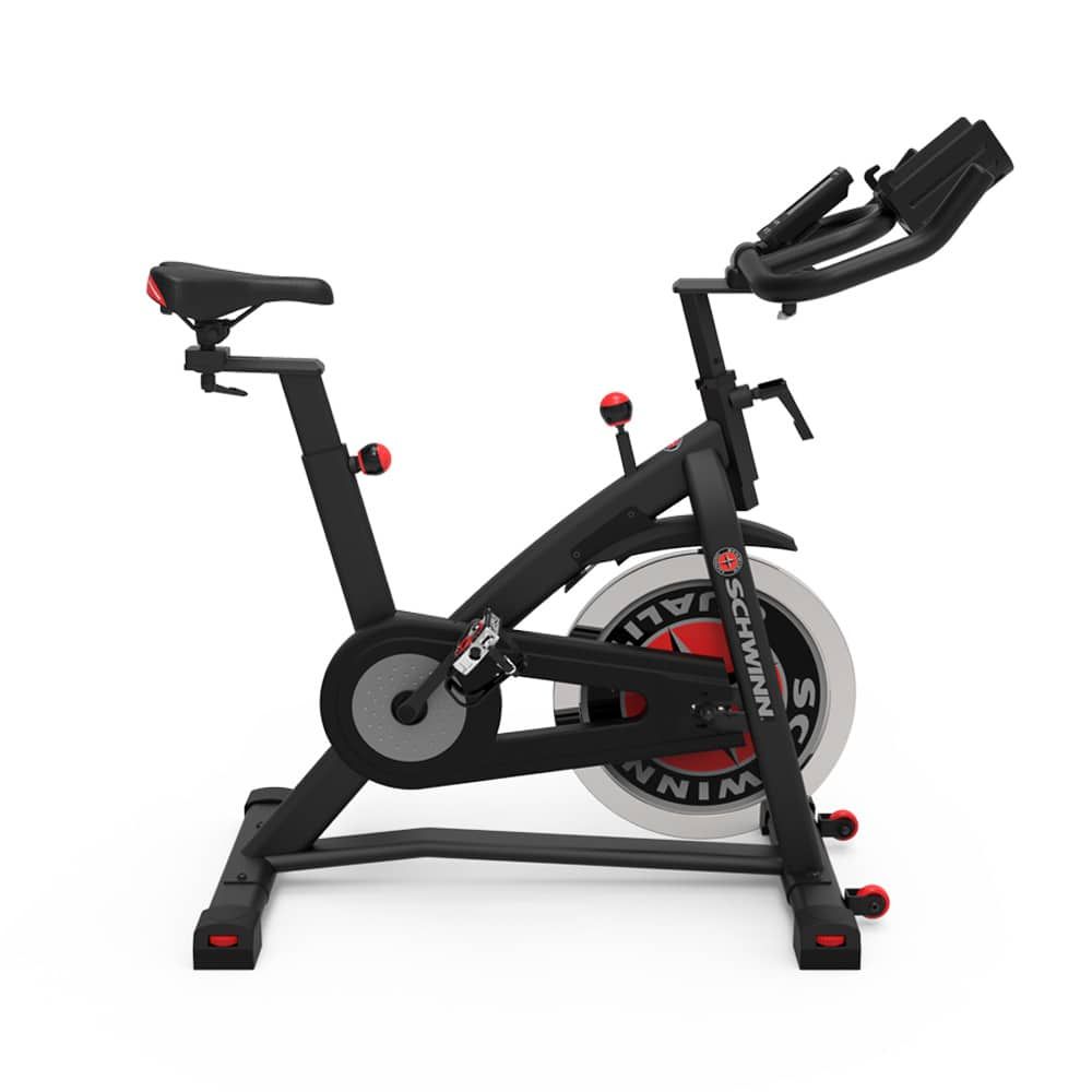 Indoor-Fahrrad. Schwarzer Rahmen, roter Akzent. Schwungrad, Pedale, Sattel und Lenker. "Schwinn"-Logo.