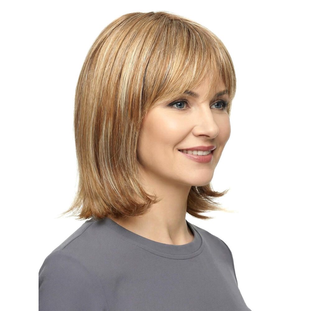 Perücke Mola von trendhair. Blond-braune Haarfarbe mit Pony. Mittellange, gestufte Frisur. Frau trägt graues Oberteil.