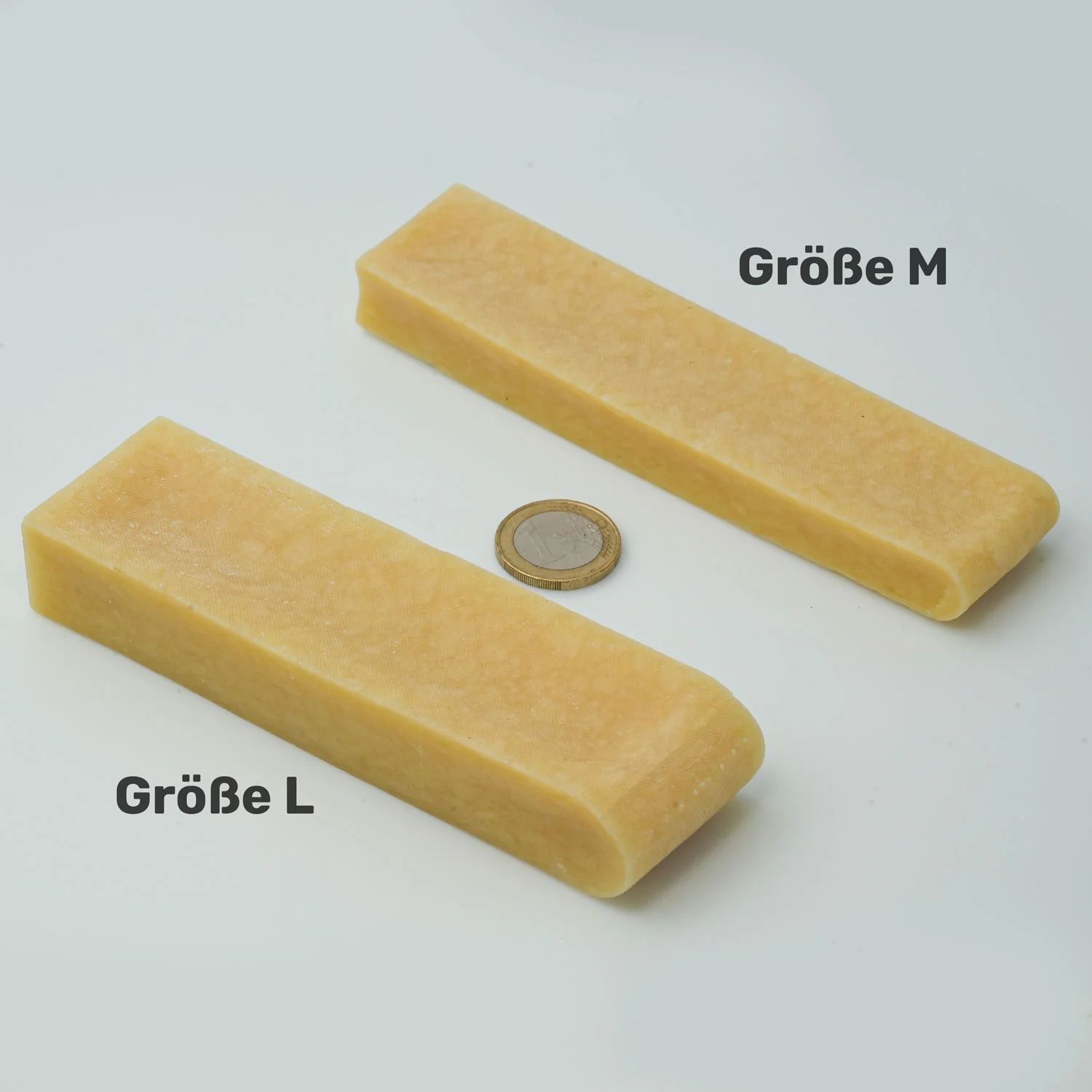 Zwei Kausnacks, Größe M und L. Eine Münze liegt daneben.