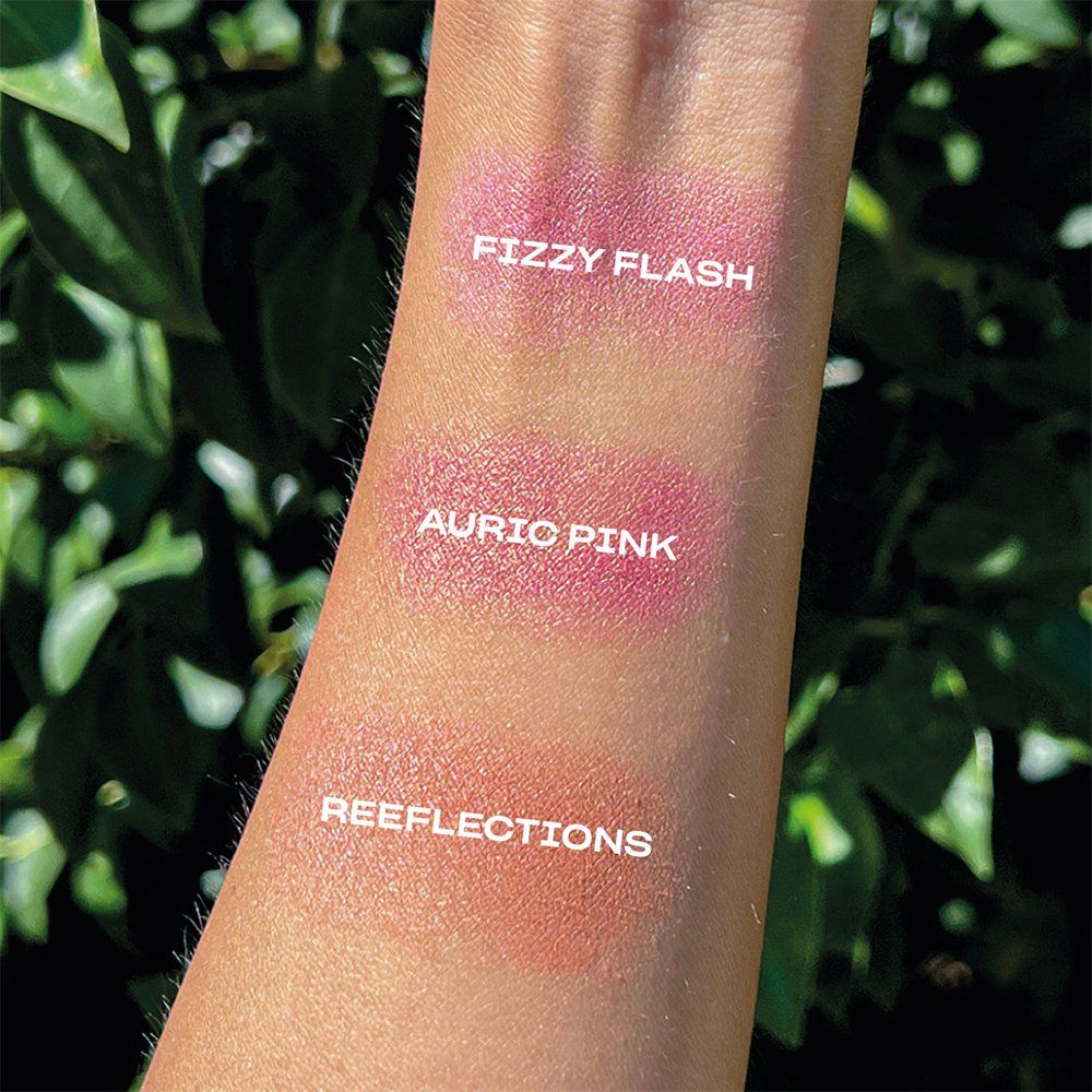 Tre colori di fard testati su un braccio. Scritte: "Fizzy Flash", "Auric Pink", "Reeflections".