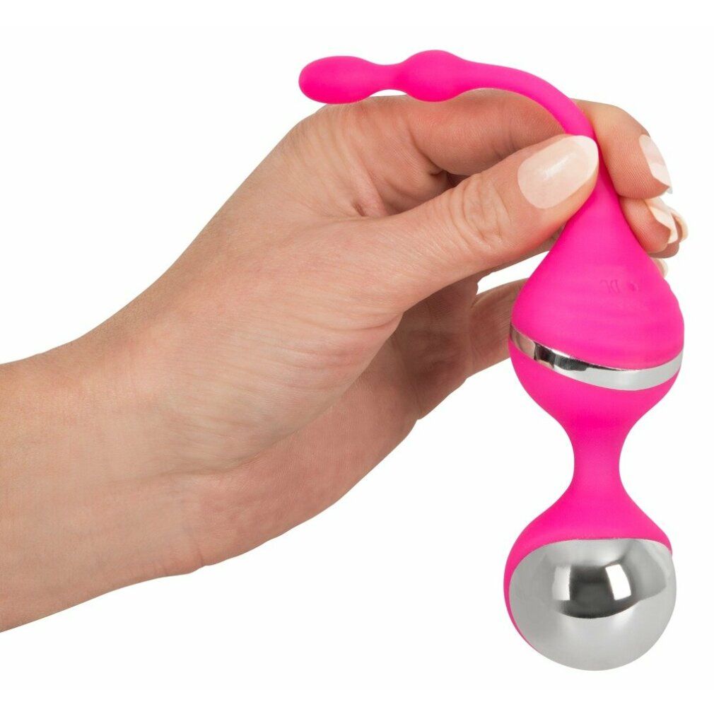 Rosa Vibrationskugel in einer Hand gehalten. Silberne Akzente und metallische Kugel. Oben drei kleine Kugeln.