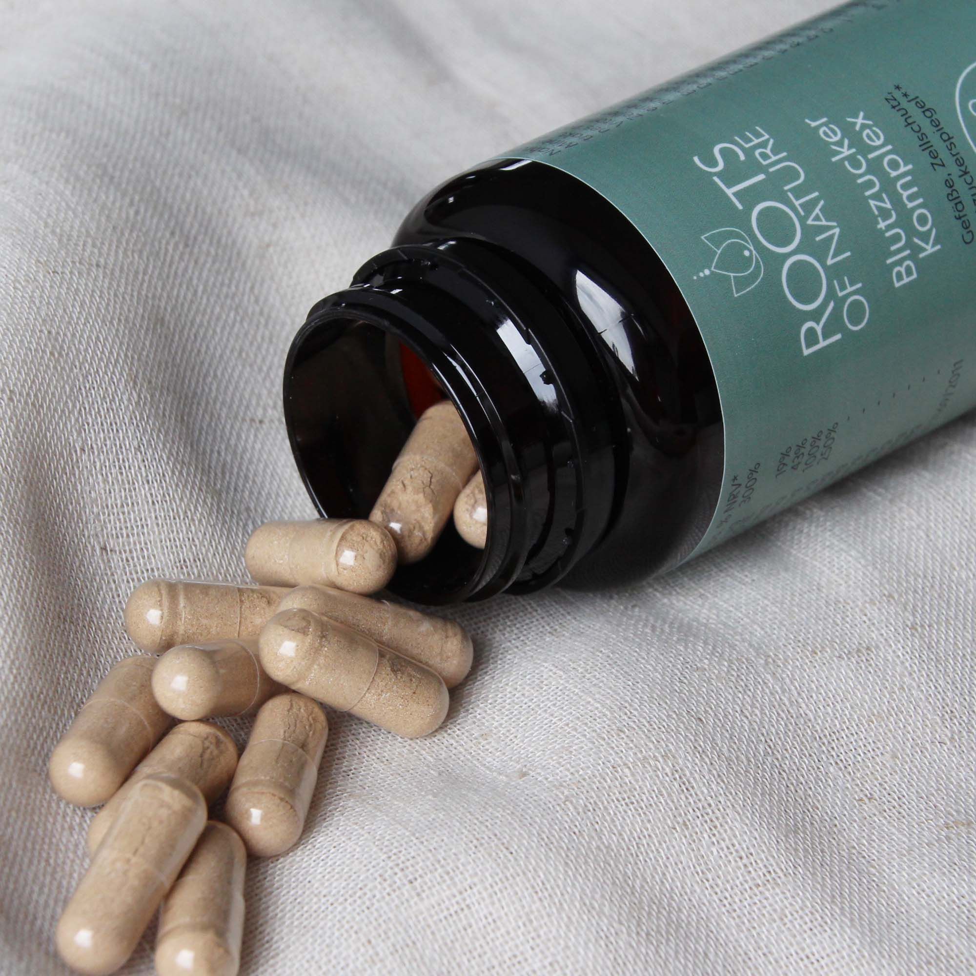 Braune Kapseln liegen neben einer geöffneten Flasche. Kapseln sind hellbraun. Flasche mit grünem Etikett.