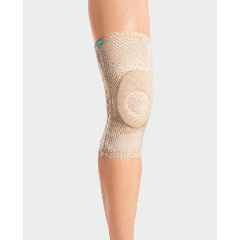 Beige Kniebandage JuzoFlex® Genu Xtra am Bein getragen. Mit Kniepolster und Markenlogo.