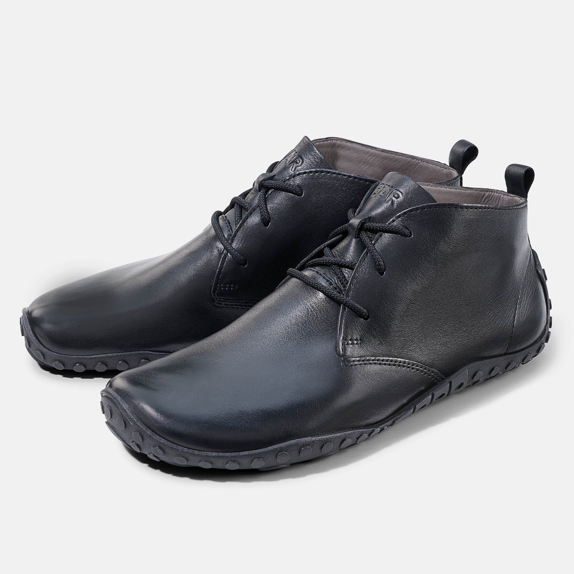 Zwei schwarze Stiefeletten. Schnürung, Zuglasche am Schaft. Sohle mit Profil. Leder.