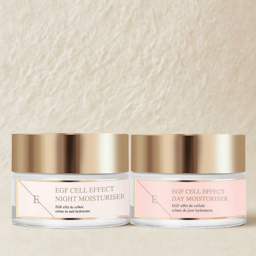 Zwei Tiegel Tages- und Nachtfeuchtigkeitscreme mit goldfarbenen Deckeln und rosa Etiketten. Die Produkte stehen nebeneinander, vor einem cremefarbenen Hintergrund.