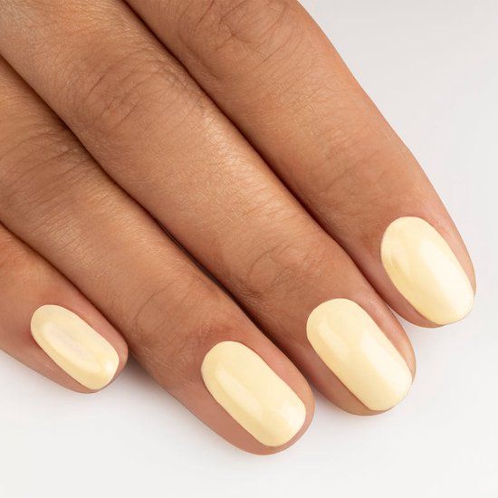 Hand mit lackierten Nägeln. Farbe: N32 Banana Cream. Glänzendes Finish. Alle Nägel lackiert.