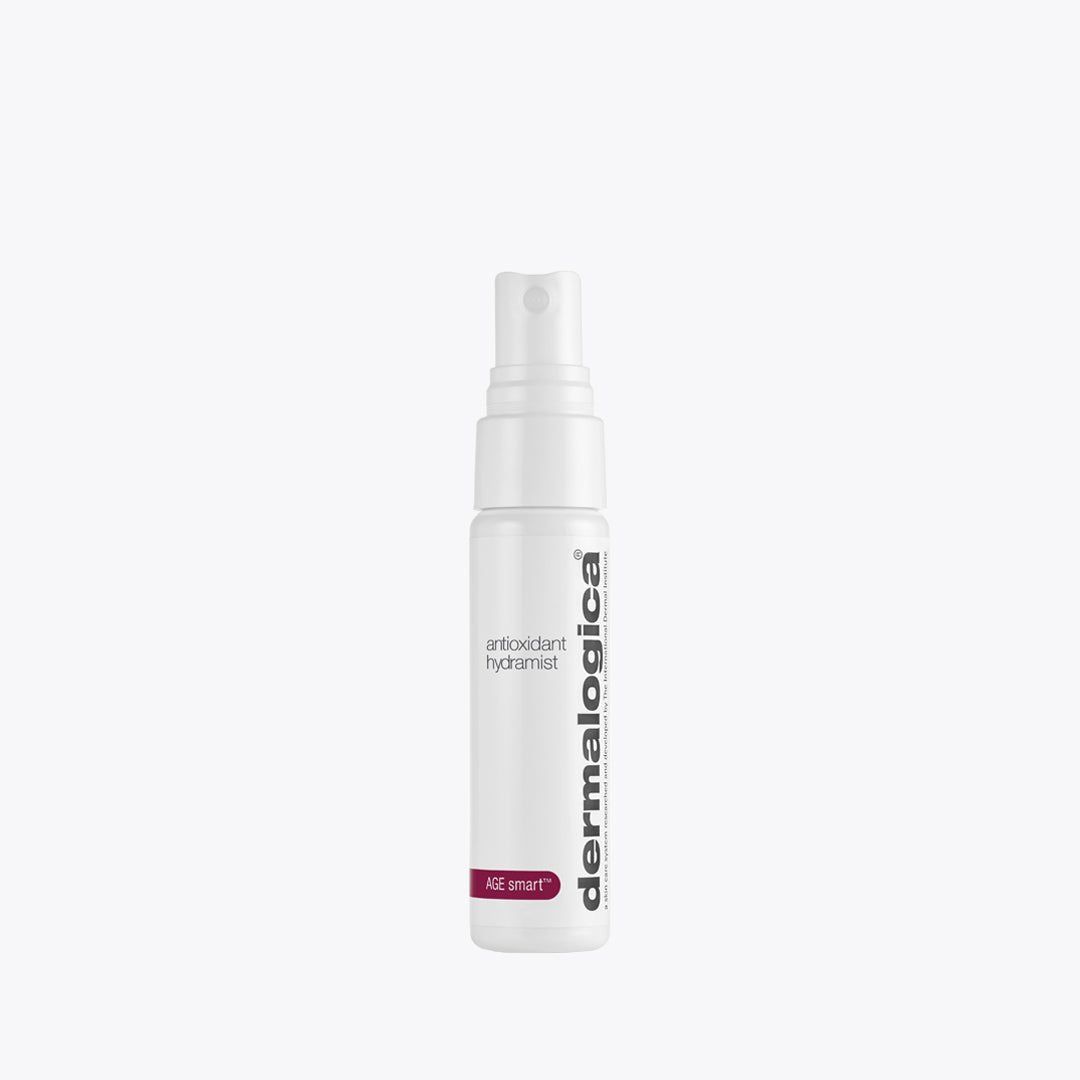 Un flacone spray bianco Dermalogica Antioxidant Hydramist. Il contenitore cilindrico ha un erogatore spray. L'etichetta riporta le parole "antioxidant hydramist" e "AGE smart". Il logo Dermalogica è visualizzato verticalmente sul lato.