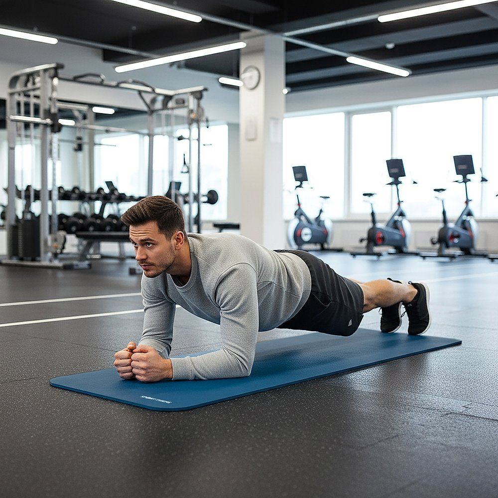 Mann trainiert auf blauer Fitnessmatte im Fitnessstudio. Liegestütz-Position. Sport-Thieme Logo sichtbar.