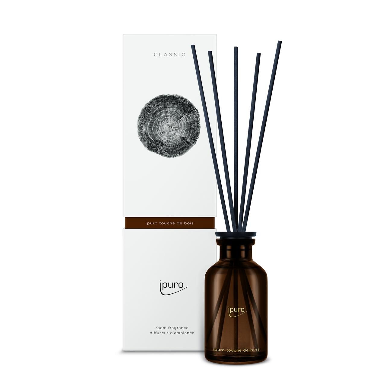 Raumduft-Diffusor mit schwarzen Stäbchen und brauner Glasflasche. Weiße Verpackung mit Holzmotiv und Schriftzug.
