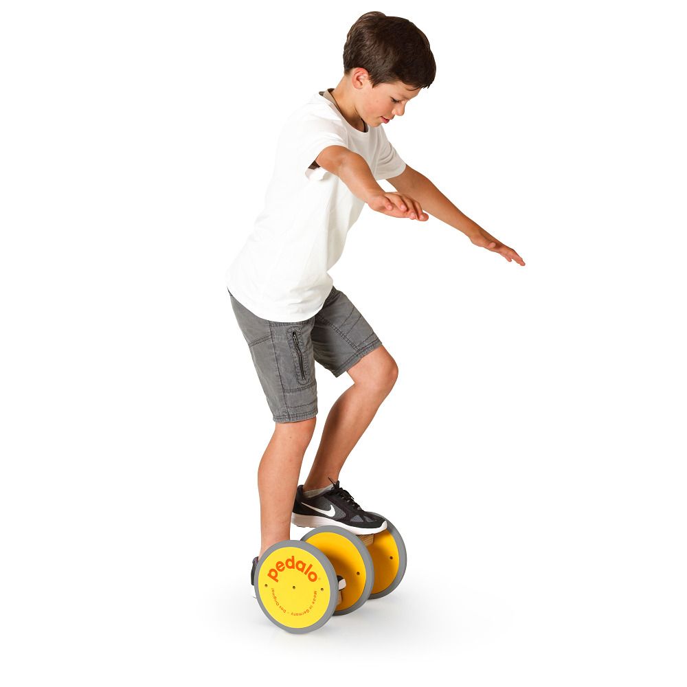 Kind auf gelbem Koordinationstrainer. Gelbe Räder, Holzkonstruktion. Logo sichtbar. Weißer Hintergrund.