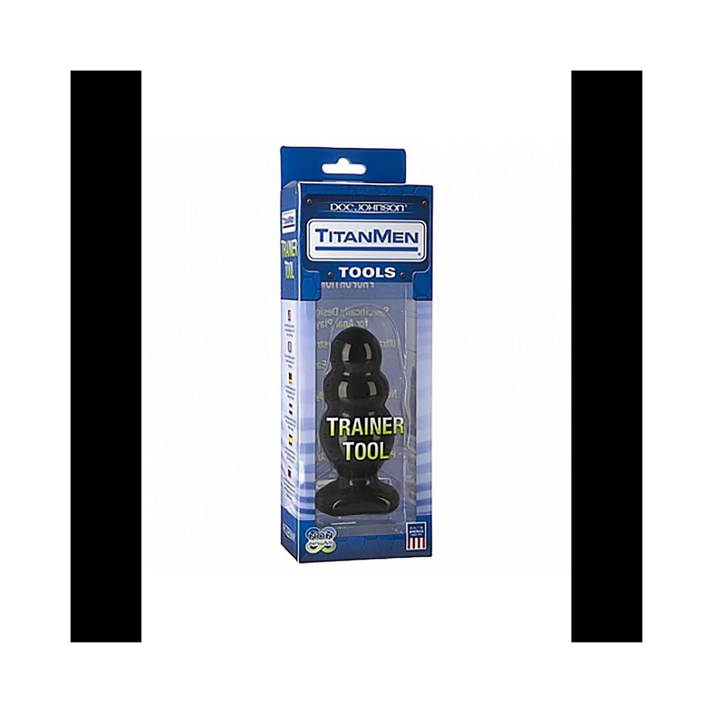 Schwarzes Wellness-Produkt in Verpackung. Aufschrift: Trainer Tool. Marke: Titanmen. Blaue Verpackung mit Sichtfenster.