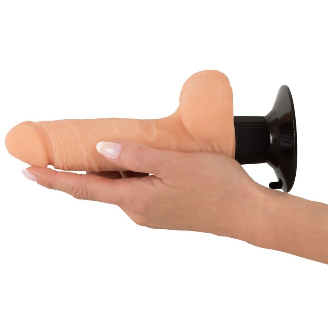 Beigefarbener, realistischer Vibrator, gehalten von einer Hand. Schwarzer Sockel. Auf weißem Hintergrund.