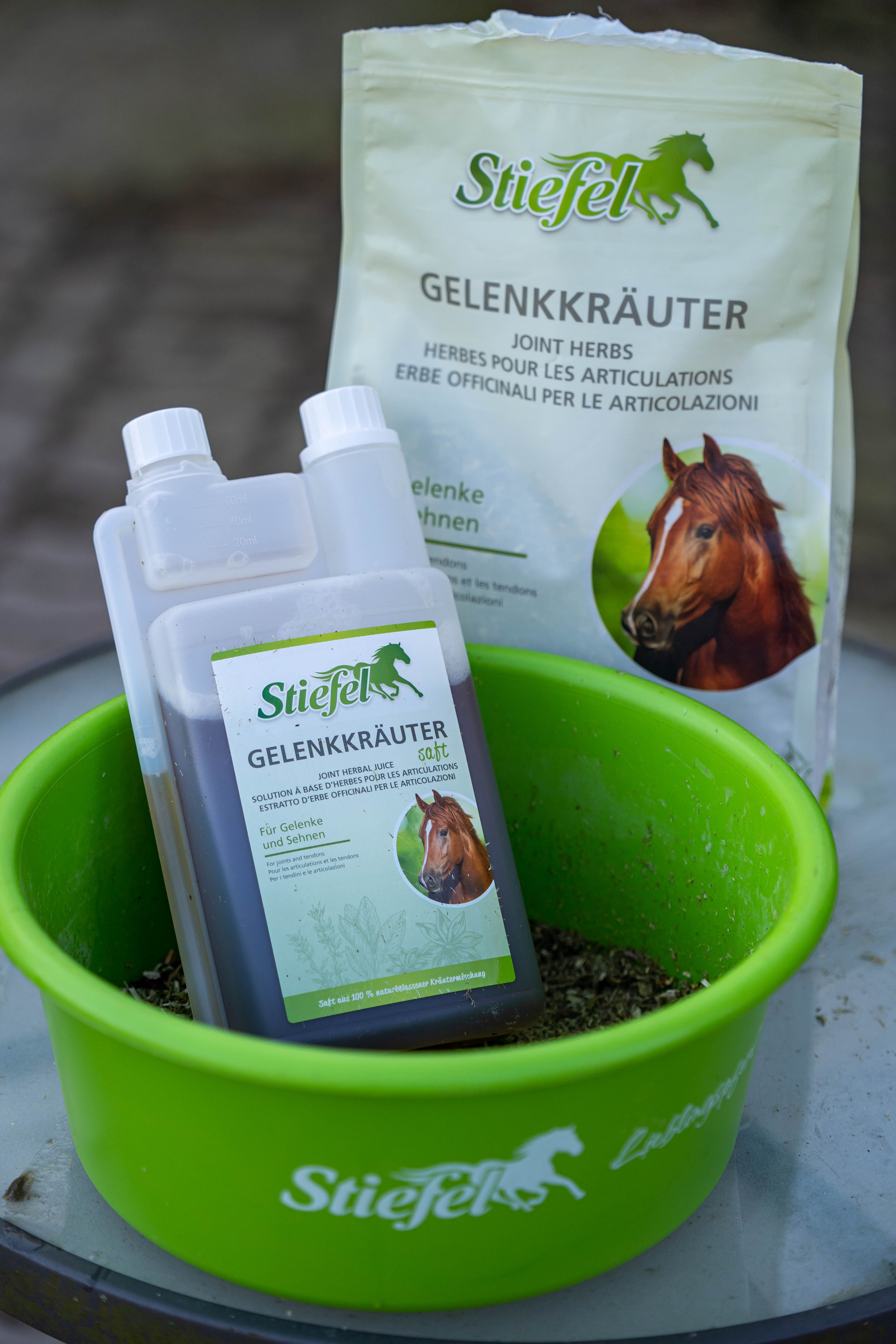 Stiefel Gelenkkräuter Saft und Kräuter in einer grünen Schüssel. Aufschrift: Joint Herbs. Daneben eine Tüte mit gleichem Aufdruck.