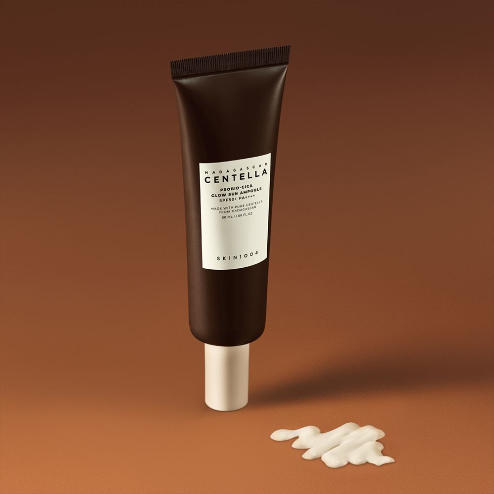 Braune Tube mit weißem Etikett. Produktname und Marke sichtbar. Daneben ein Klecks Creme. Auf braunem Hintergrund.