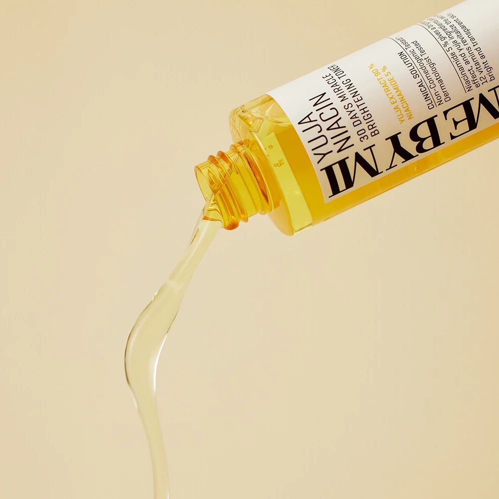 Gelbe Flüssigkeit fließt aus einer Flasche mit weißem Etikett. Text: Yuja Niacin, 30 Days Miracle Brightening Toner.