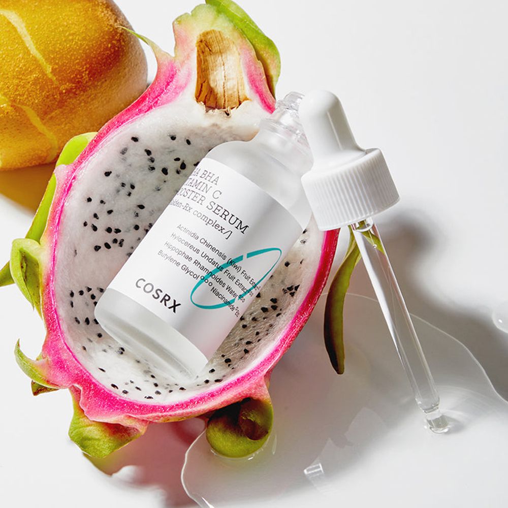 Serumflasche mit Pipette, neben einer halbierten Drachenfrucht. Aufschrift: COSRX AHA BHA Vitamin C Booster Serum.
