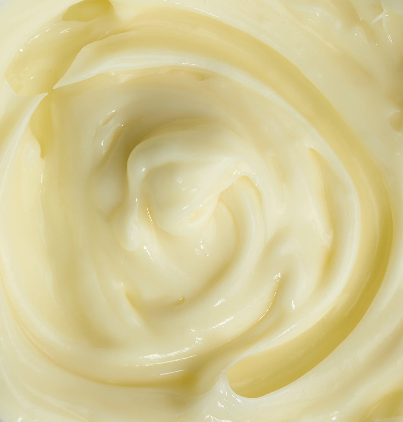 Nahaufnahme einer cremigen, gelblichen Gesichtsmaske. Die Textur ist gewirbelt.