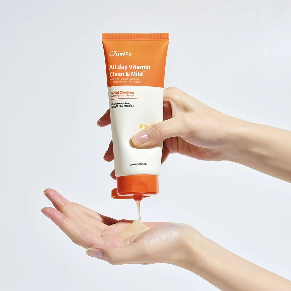 Hände halten eine Tube "JUMISO All Day Vitamin Clean & Mild" und geben eine Flüssigkeit ab.