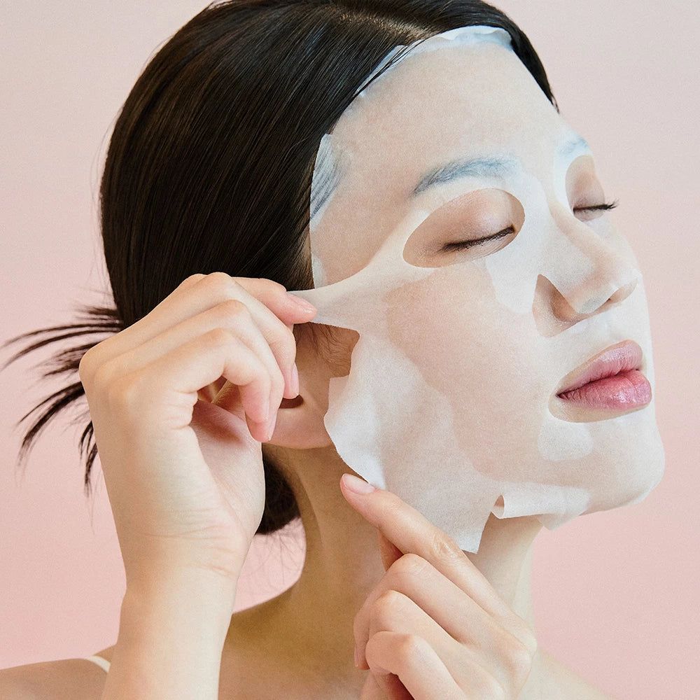 Frau mit geschlossenen Augen, die eine Gesichtsmaske aufträgt.