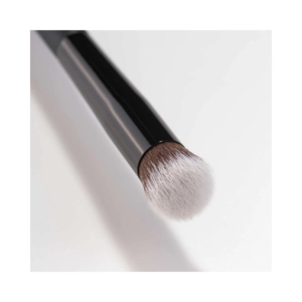 Pinsel mit schwarzem Griff und hellem Pinselkopf. Nahaufnahme, diagonale Ansicht.