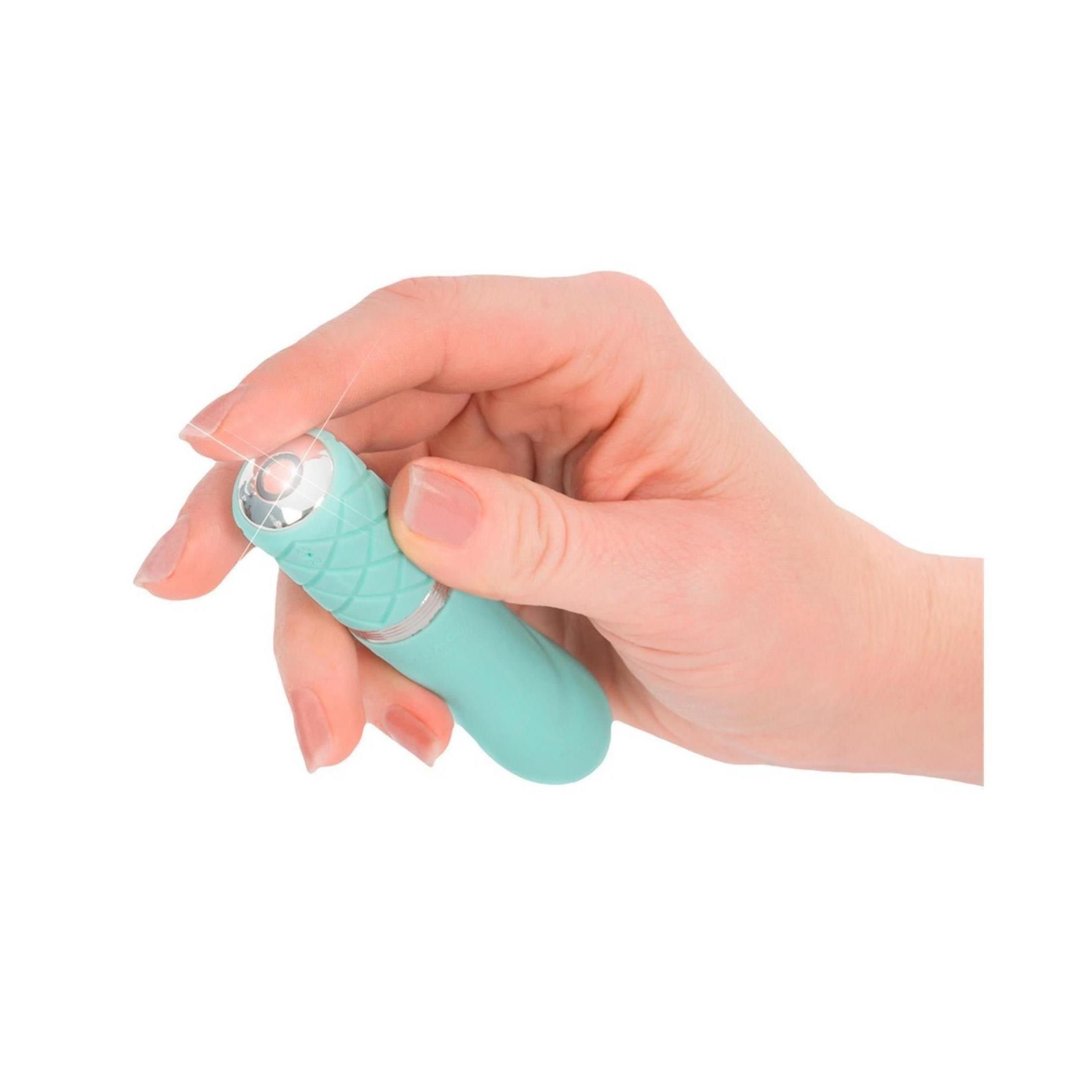 Türkisfarbener Vibrator in einer Hand gehalten. Silberner Ring und rautenförmiges Muster am Griff.