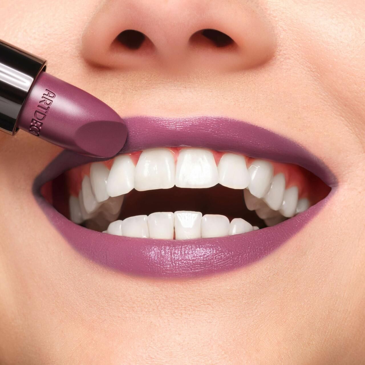 Person mit geöffnetem Mund. Ein Lippenstift mit der Aufschrift Artdeco wird auf die Lippen aufgetragen.